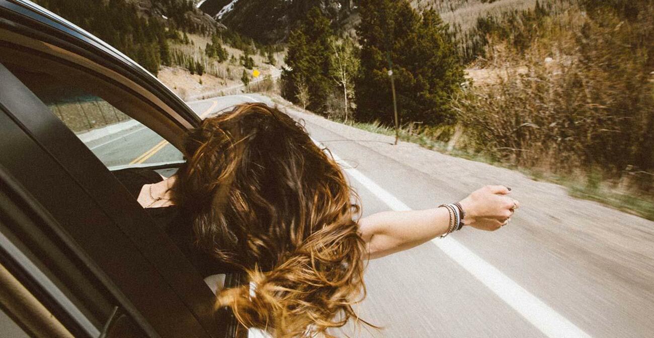 Mujer asomando por la ventanilla en un viaje