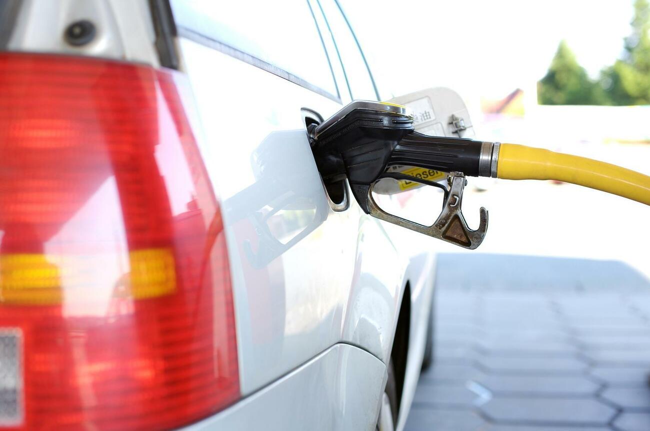 Un automóvil con la manguera de gasolina llenando su depósito Un automóvil con la manguera de gasolina llenando su depósito
