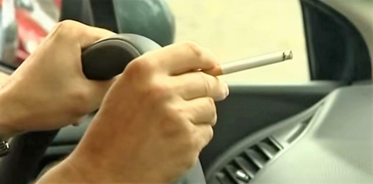 Un conductor fumando mientras conduce su coche