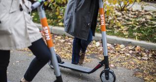 Dos personas circulan con el patinete eléctrico Spin por una acera Dos personas circulan con el patinete eléctrico Spin por una acera