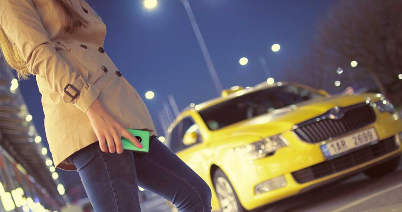 Mujer solicitando un vehículo VTC con su móvil delante de un taxi / PIXABAY Mujer solicitando un vehículo VTC con su móvil delante de un taxi / PIXABAY