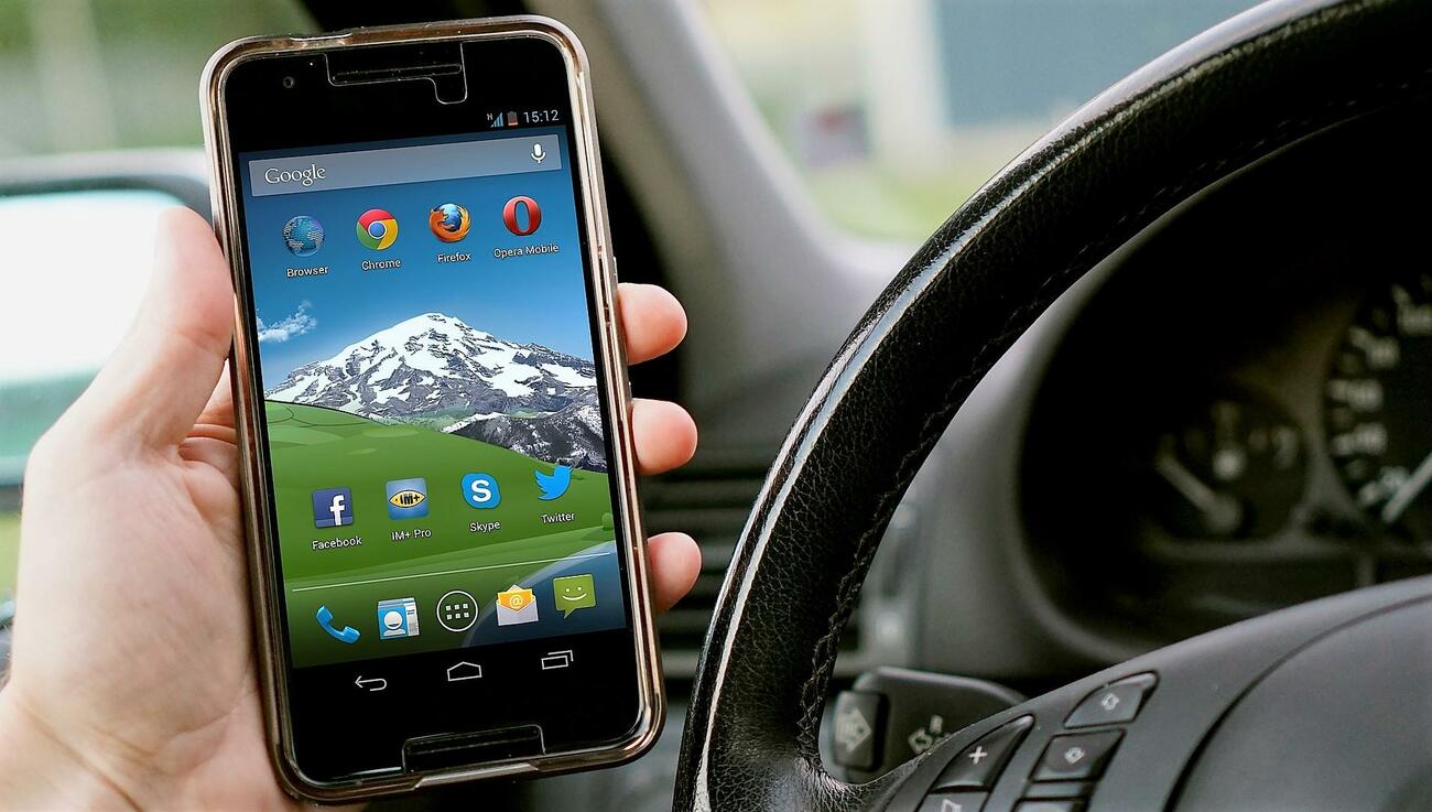 Un conductor utiliza el teléfono móvil en un coche Un conductor utiliza el teléfono móvil en un coche