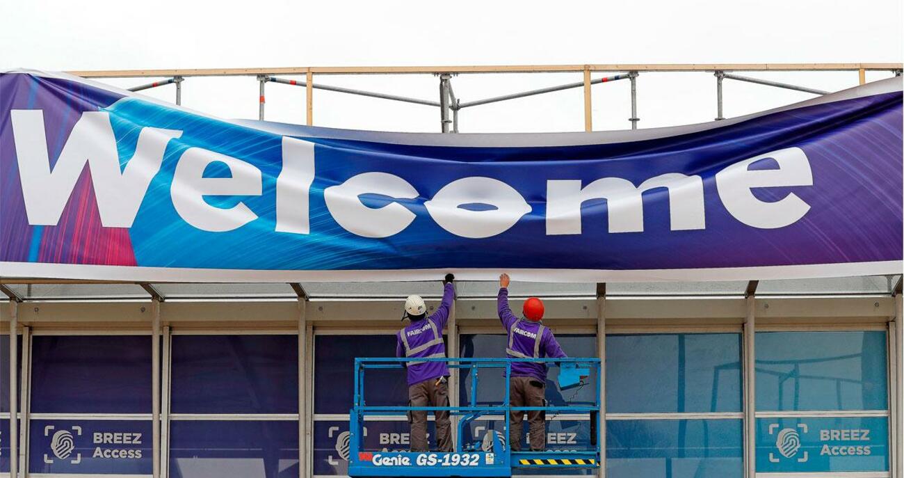 Operarios desmontando una de las pancartas de bienvenida del Mobile World Congress de Barcelona / EFE