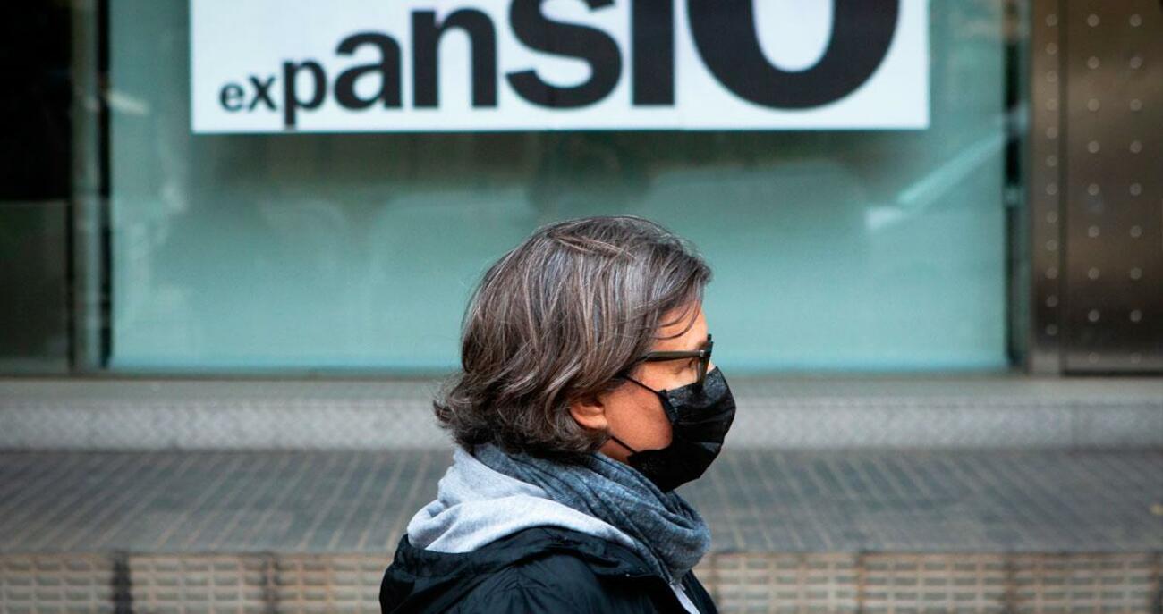 Una persona pasa delante de un banco durante la epidemia de coronavirus